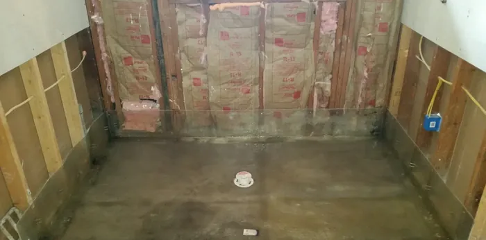 Shower pan sloped to a capped drain, membrane turned up the base of the surrounding insulated walls